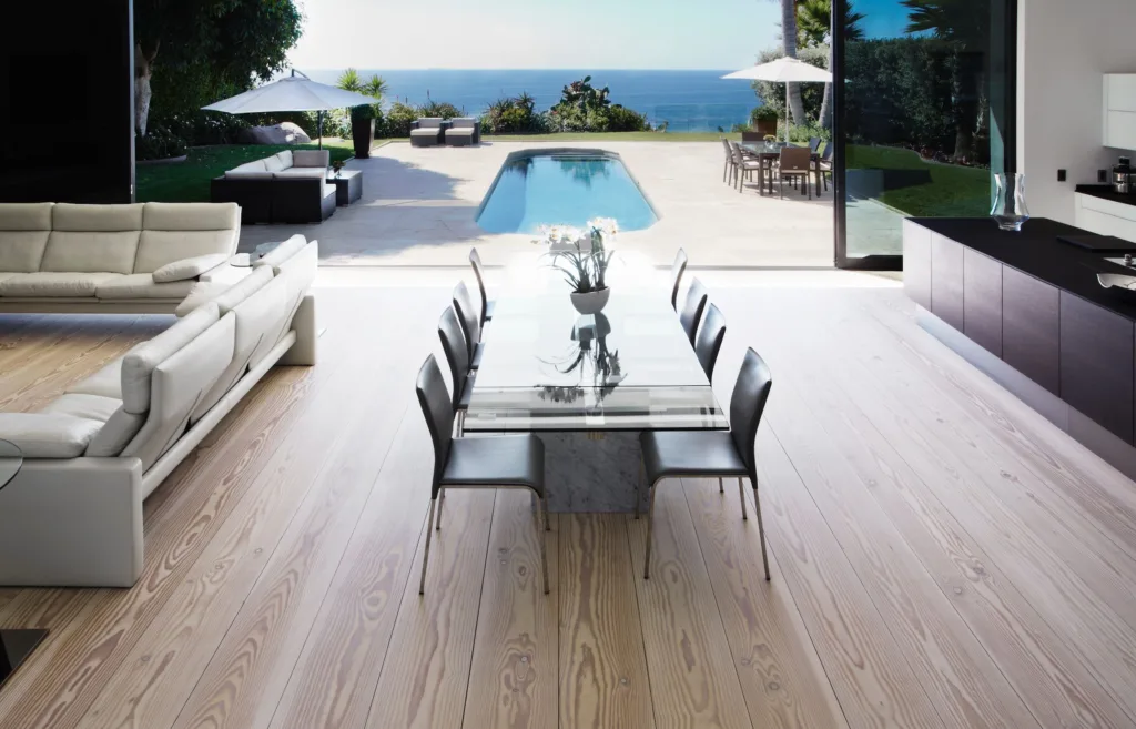 Salón-comedor con tablas Dinesen de gran longitud abierto a la terraza y la piscina