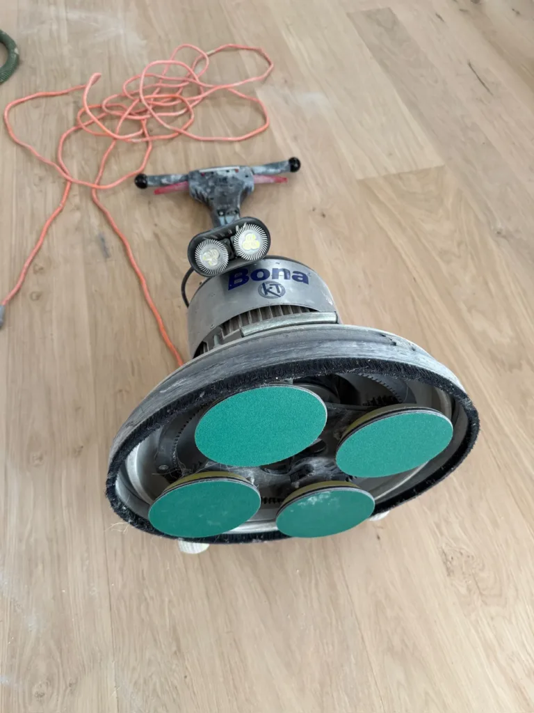 Lijadora Bona FlexiSand 1.9 con el plato multidisco y cuatro discos de lija Bona sobre un suelo de roble