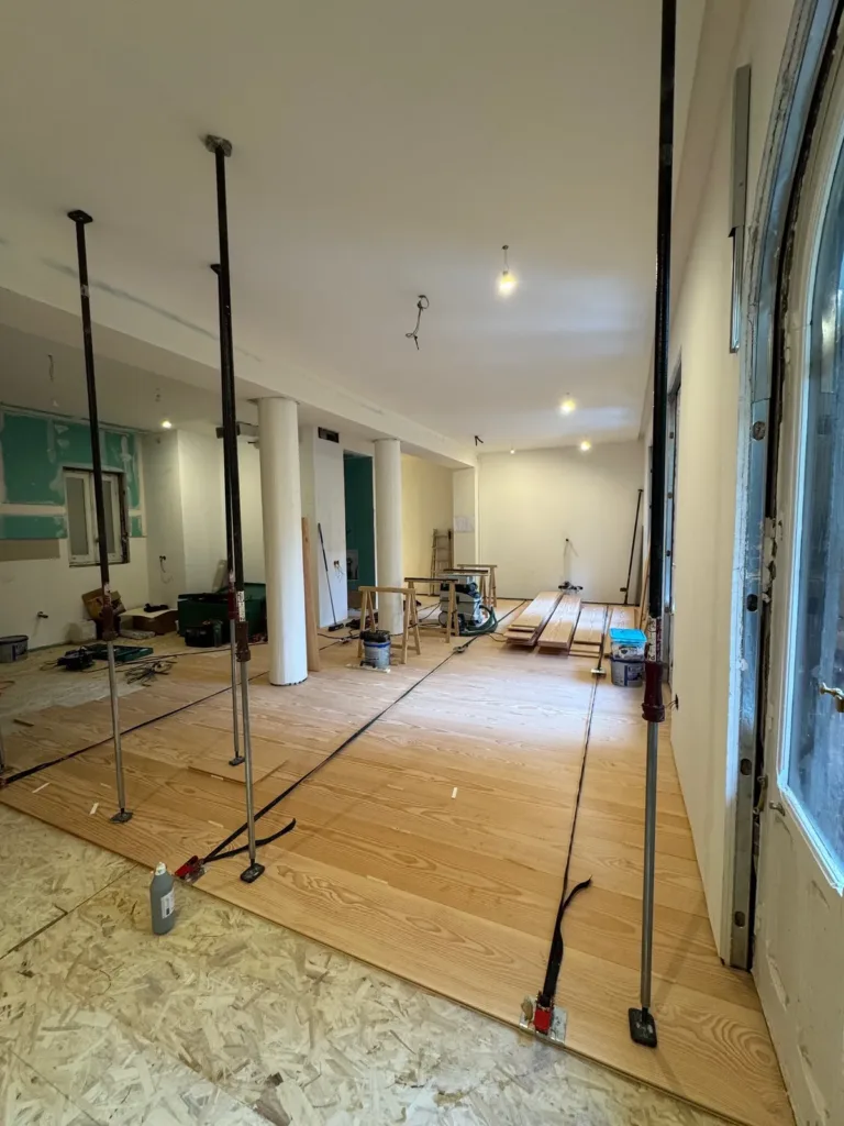 Estancia en obra con tablas largas de Douglas recién encoladas y apretadas con puntales