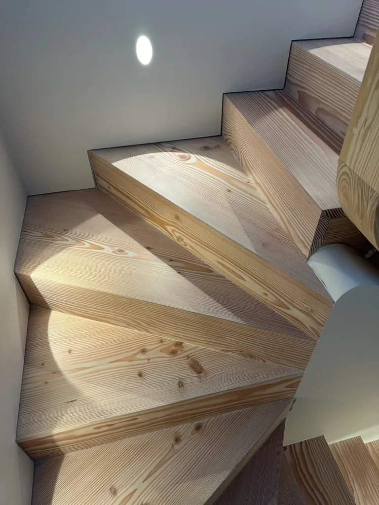 Detalle de los peldaños compensados de una escalera de madera, con luz rasante sobre la veta