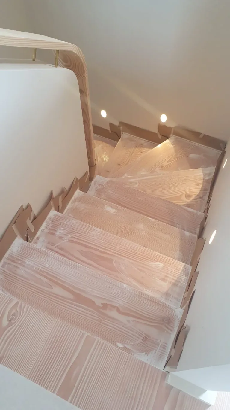 Escalera compensada de madera con los paramentos enmascarados con papel mientras se da el acabado de Dinesen Lye y Dinesen White Oil 2K