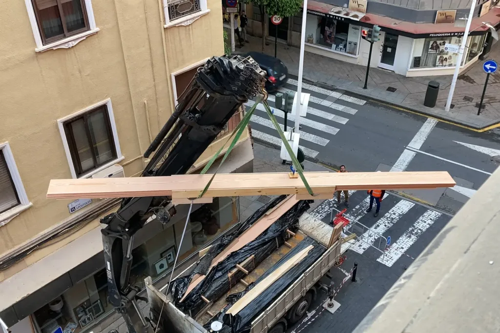 Grúa izando desde el camión un paquete de tablas Dinesen Douglas de 350 mm hasta la vivienda