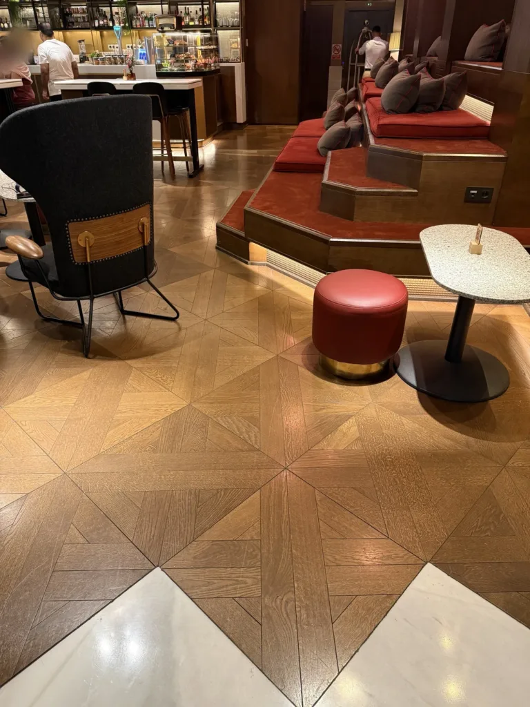 Suelo de losetas de roble teñido en Ondas, el vestíbulo del Hyatt Centric Gran Vía Madrid, junto al pavimento de mármol blanco