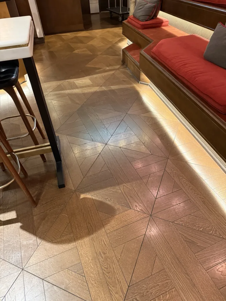 Losetas cuadradas de roble teñido con las diagonales marcadas junto a la barra de Ondas, Hyatt Centric Gran Vía Madrid