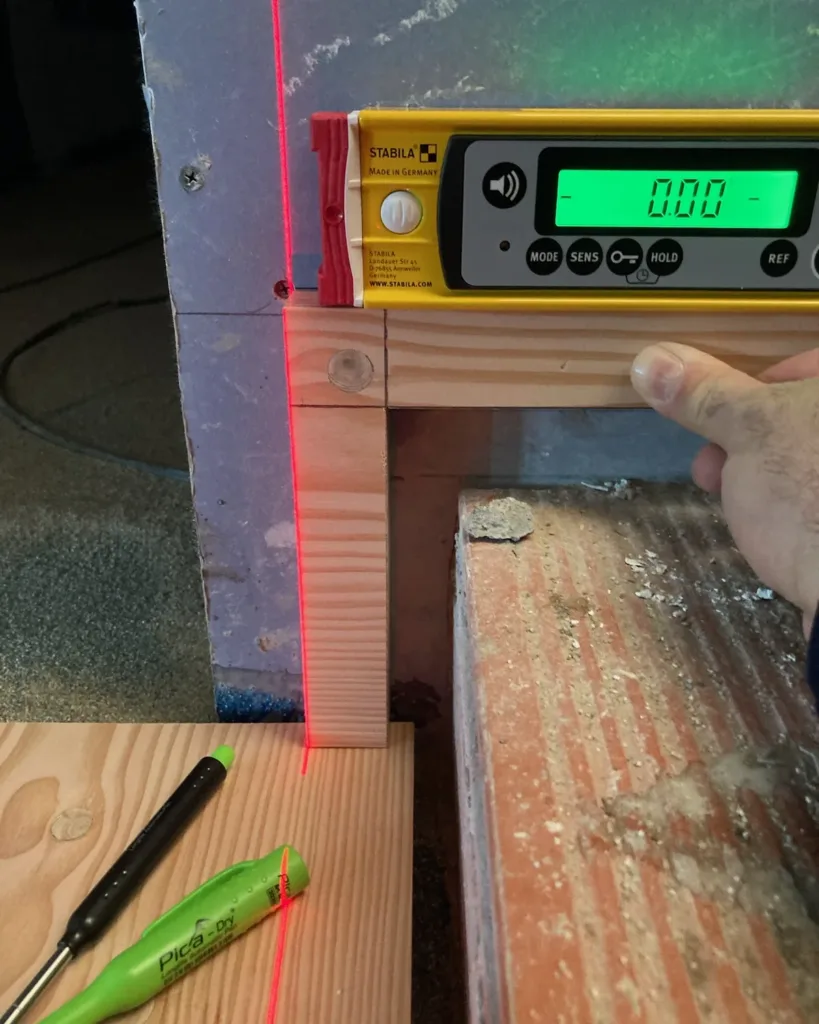 Nivel electrónico marcando 0,00° y línea láser sobre rastreles de pino apoyados en el forjado
