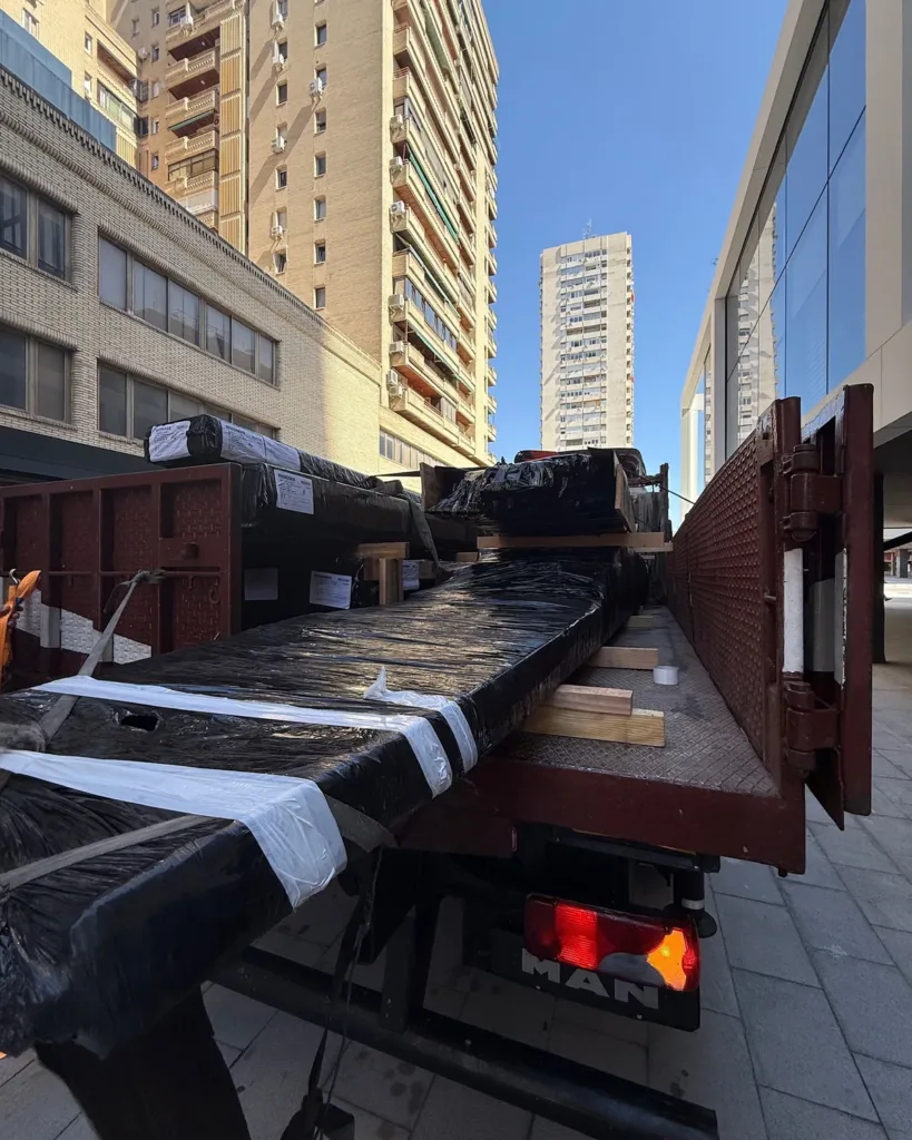 Paquetes de tablas Dinesen embalados y flejados sobre la plataforma del camión, a pie de obra