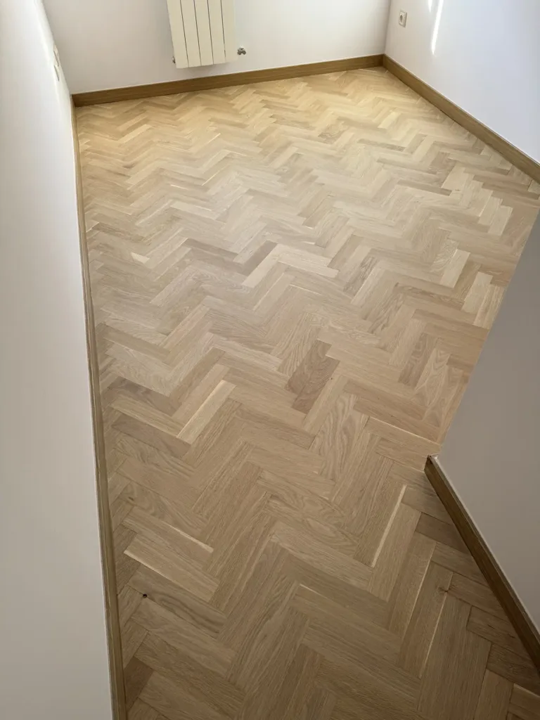 Parquet de roble en espiga barnizado en mate a lo largo de un dormitorio con rodapié de roble, piso con mirador en Madrid