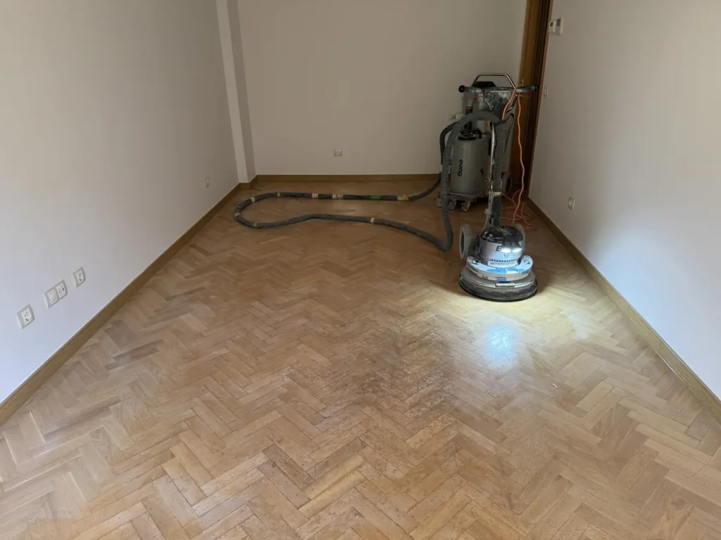 Lijadora Bona FlexiSand conectada por manguera al aspirador Bona DCS 70 durante el acuchillado de un parquet de roble en espiga, piso con mirador en Madrid
