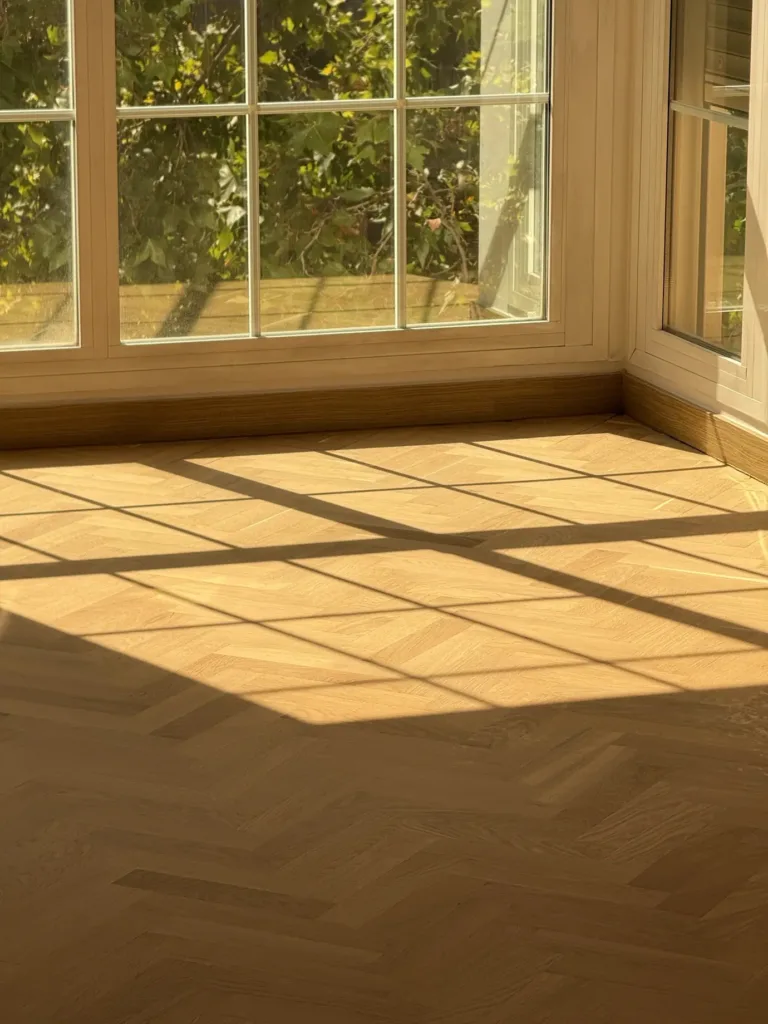 Sombra de la carpintería del mirador sobre el parquet de roble en espiga barnizado con Bona Traffic HD Raw, piso con mirador en Madrid