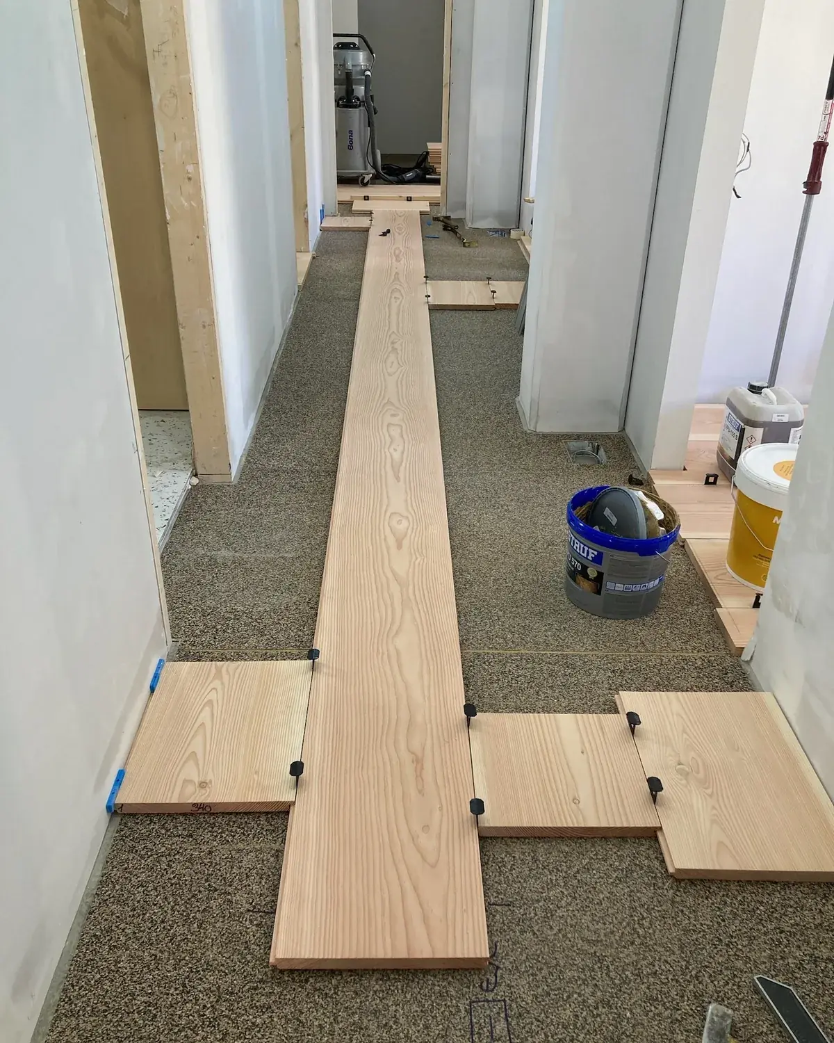 Replanteo en seco de tablas Douglas sobre manta de corcho y caucho, con el adhesivo preparado en el pasillo