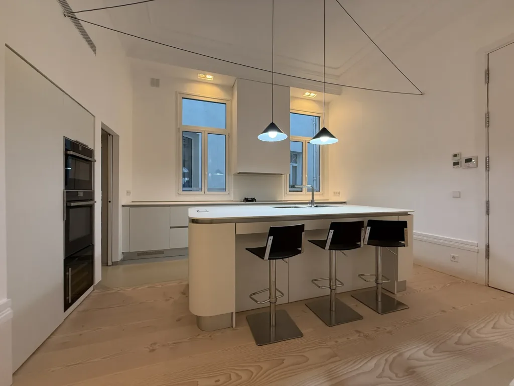 Cocina con isla y taburetes sobre el suelo Dinesen Douglas restaurado, vivienda en el barrio de Palacio (Madrid)
