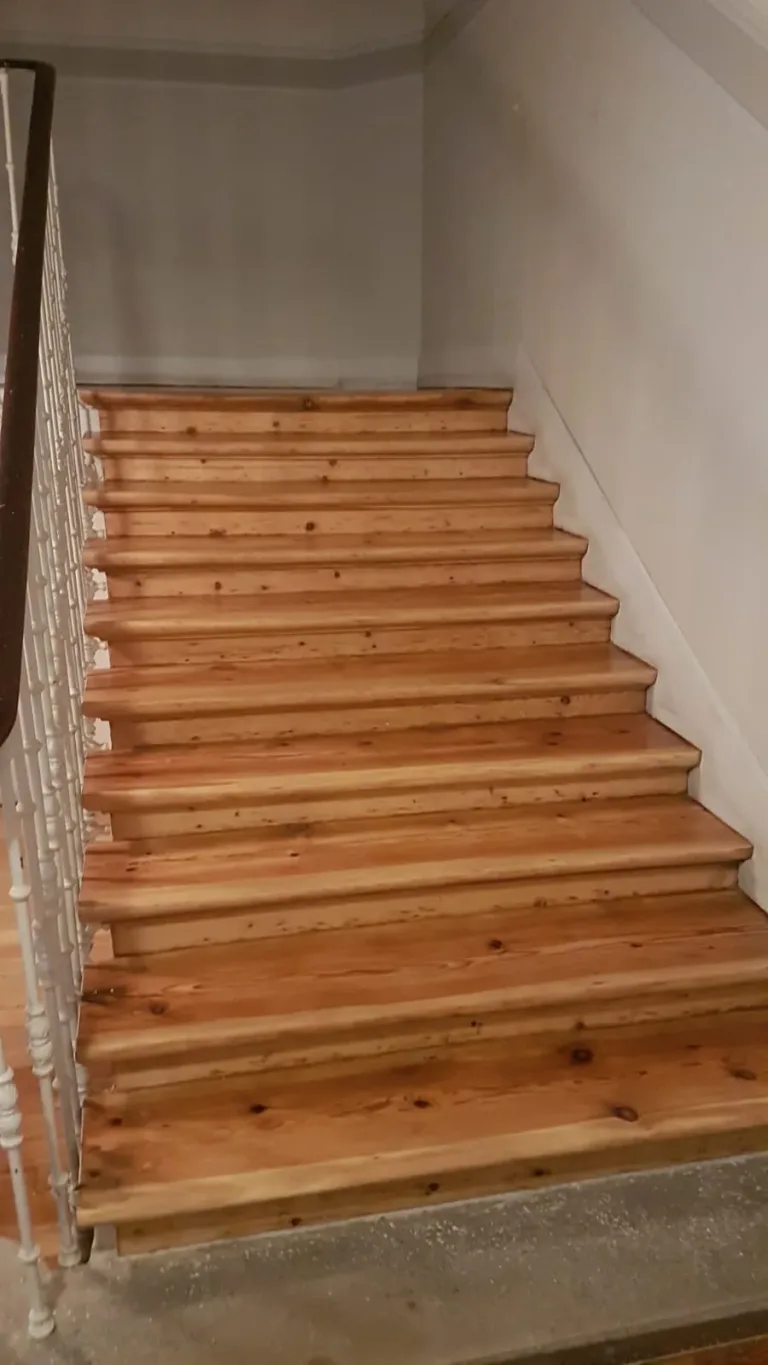 Peldaños de una escalera antigua de madera restaurados, con el mamperlán redondeado