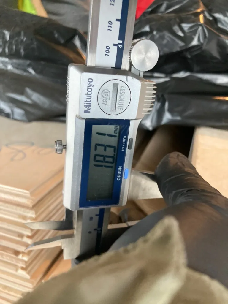 Calibre digital midiendo el espesor de una tabla de roble multicapa en la recepción del material