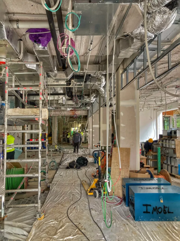 Planta primera del edificio Santoña, en el Campus Acciona (Madrid), en obra, con las instalaciones a la vista y la solera protegida, antes del suelo de madera