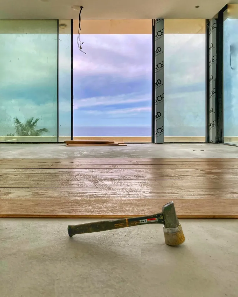 Sala en obra con las primeras tablas colocadas y el mar al fondo tras la cristalera