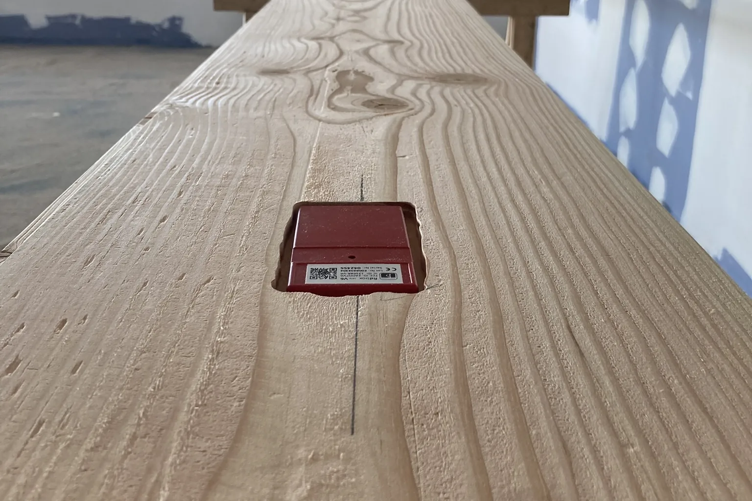 Sensor Fidbox embutido en el dorso de una tabla Douglas para registrar temperatura y humedad bajo el suelo