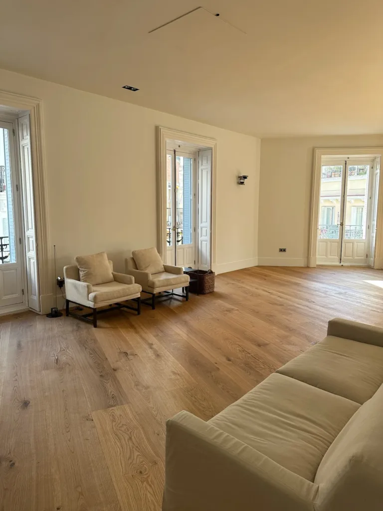 Salón con sofá y butacas de lino sobre suelo Dinesen HeartOak, vivienda en la calle Antonio Flores, Madrid