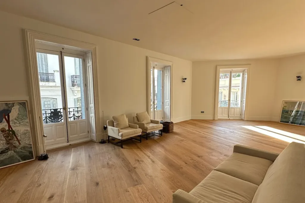Salón con tres balcones y suelo de madera Dinesen HeartOak encolado sobre suelo radiante, vivienda en la calle Antonio Flores (Madrid)