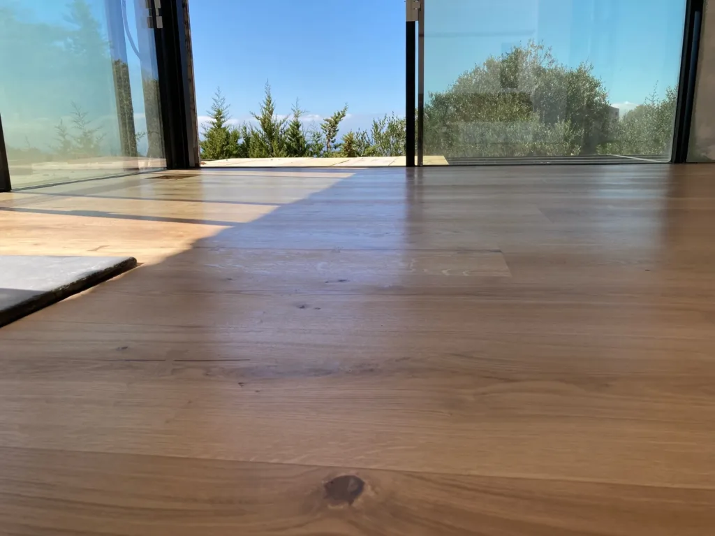 Suelo Dinesen HeartOak a ras de la cristalera abierta, con el pinar y el mar al fondo, vivienda en Betijuelo (Tarifa)