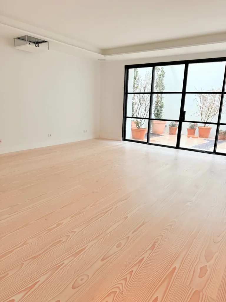 Salón con ventanal de acero al patio y suelo Dinesen Layers Douglas Classic acabado con lejía y jabón blanco