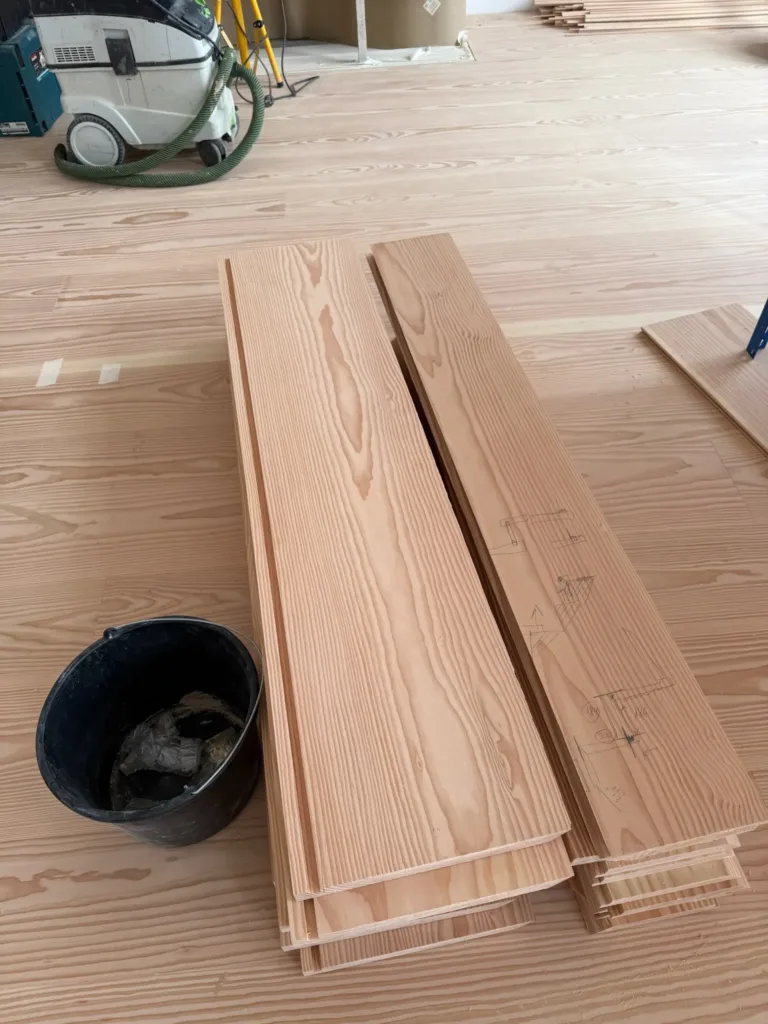 Tablas Dinesen Layers Douglas Classic apiladas en obra con croquis de despiece a lápiz