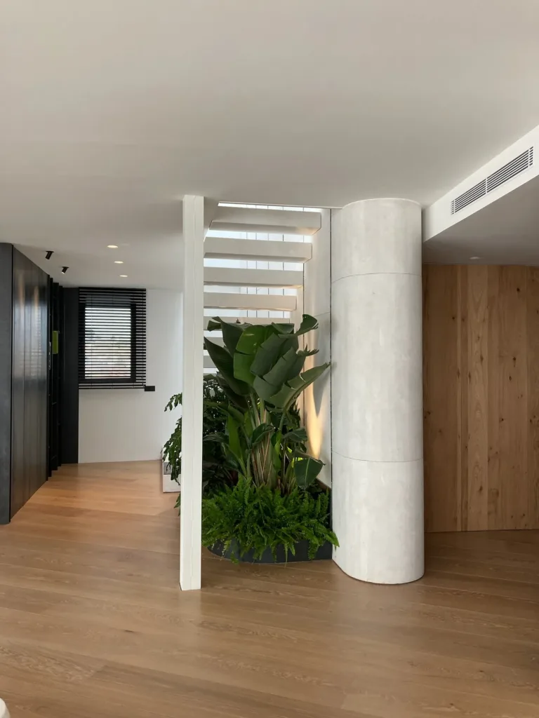 Pilar curvo, escalera volada y plantas, con el suelo Dinesen Oak Classic continuo hacia el pasillo, vivienda en la Costa Blanca
