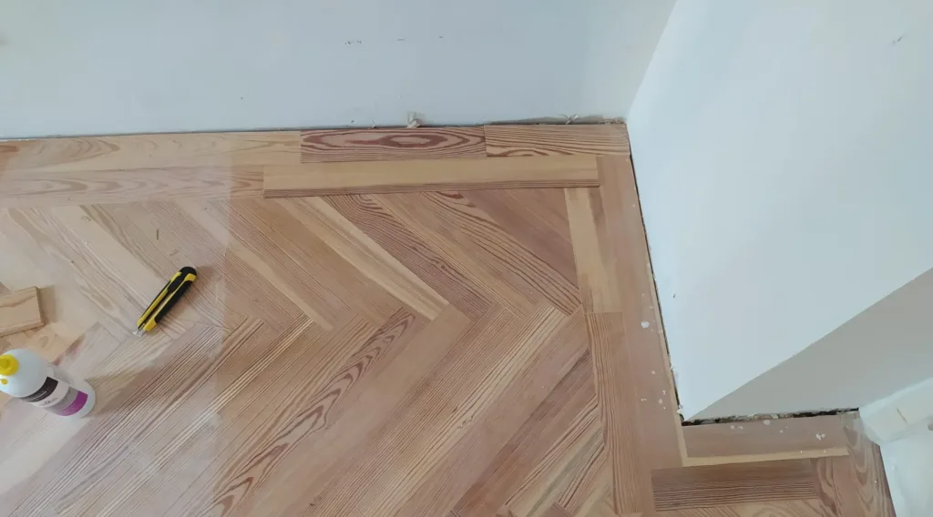 Colocación de la espiga de pino melis viejo con cenefa de tablas rectas junto a la pared, vivienda en la calle Francisco de Rojas (Madrid)
