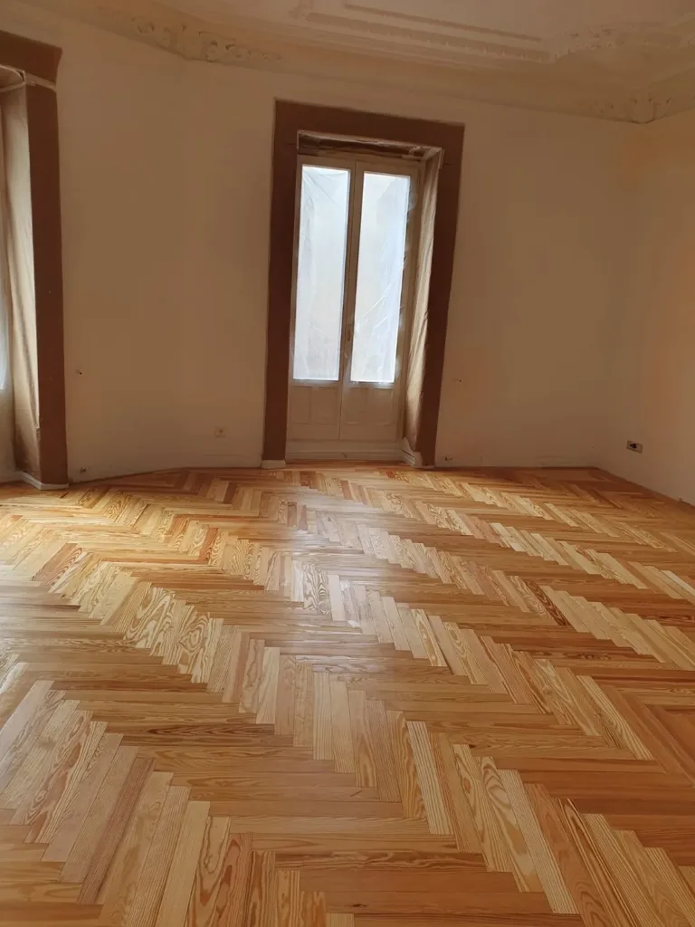 Dormitorio con balcón a la calle y suelo de espiga de pino melis viejo, vivienda en la calle Francisco de Rojas (Madrid)