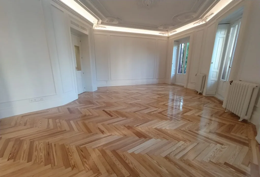 Salón con balcones a la calle y suelo de espiga de pino melis viejo barnizado en brillo, vivienda en la calle Francisco de Rojas (Madrid)