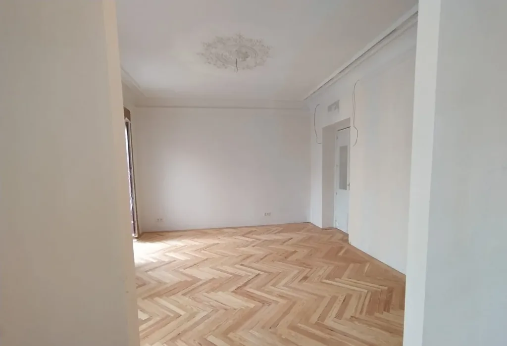 Salón con rosetón de escayola y suelo de espiga de pino melis viejo recién lijado, vivienda en la calle Francisco de Rojas (Madrid)