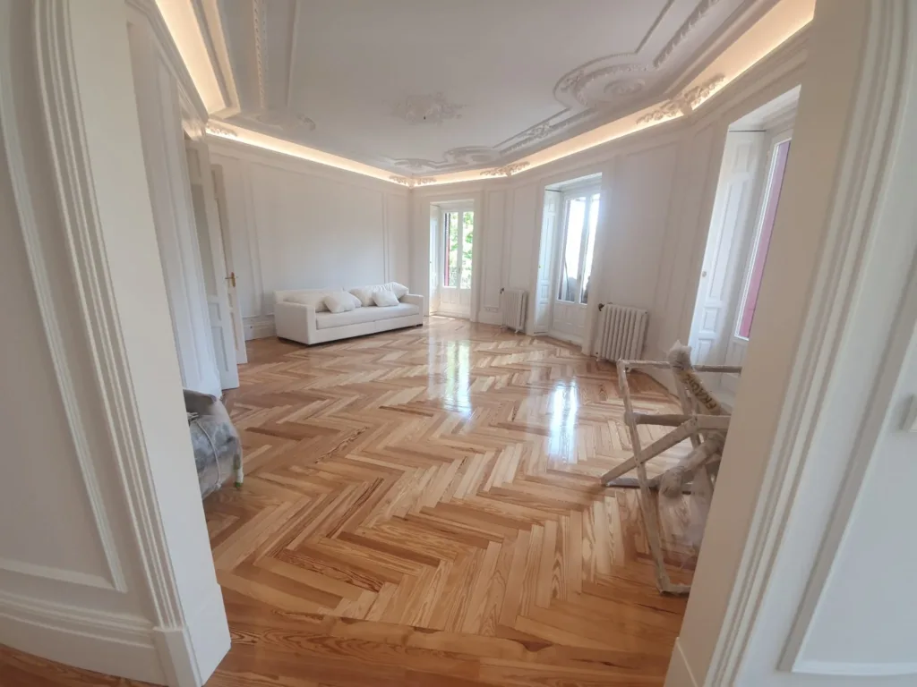 Salón con techos de escayola, luz indirecta y suelo de espiga de pino melis viejo barnizado, vivienda en la calle Francisco de Rojas (Madrid)