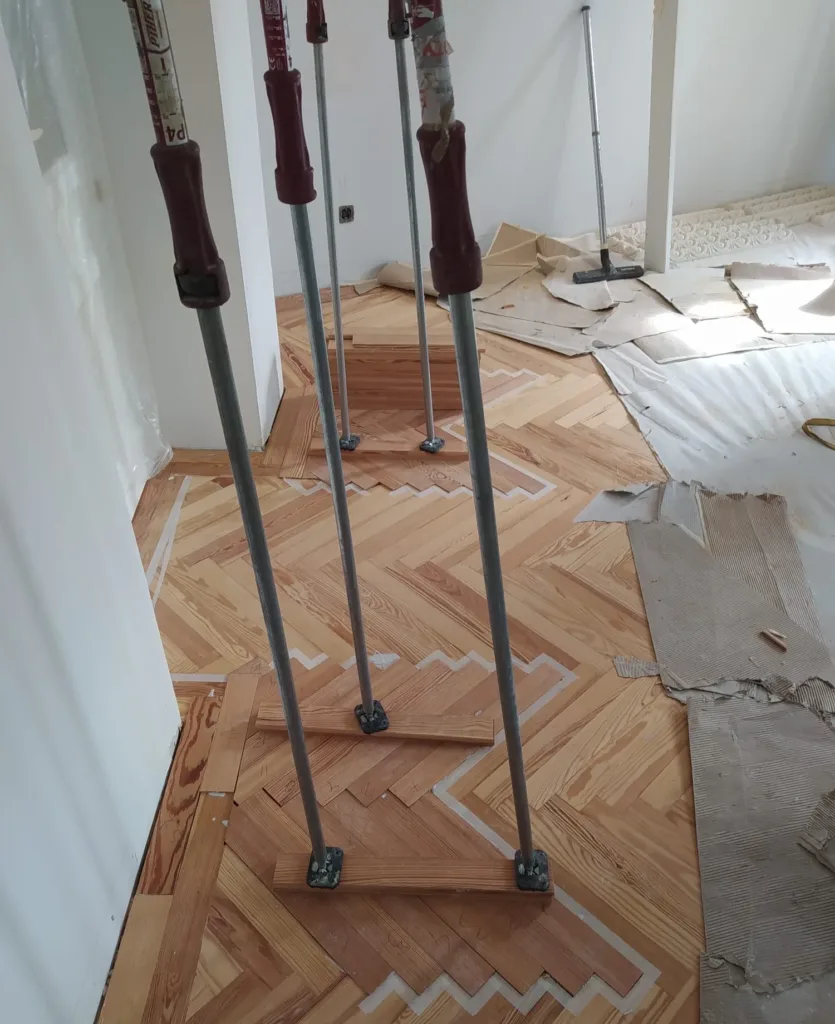 Tablillas de pino melis viejo numeradas y encoladas en el hueco de la espiga antigua, apretadas con puntales mientras seca el adhesivo, vivienda en la calle Francisco de Rojas (Madrid)