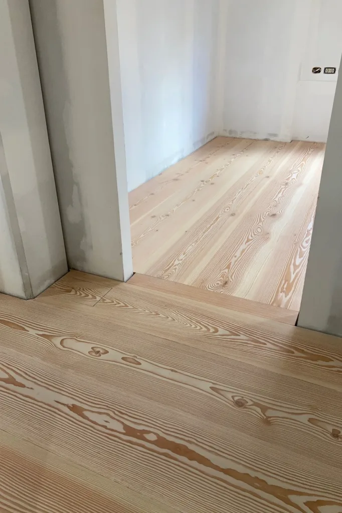 Paso entre estancias con tabla de cruce perpendicular en el suelo Dinesen Douglas, vivienda de la calle Villacís, Murcia
