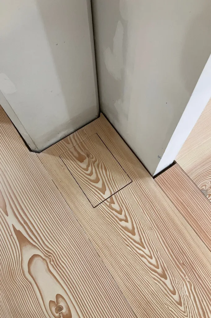 Registro de toma de suelo integrado en la tabla Dinesen Douglas junto a un paso, con la tapa cortada de la misma pieza