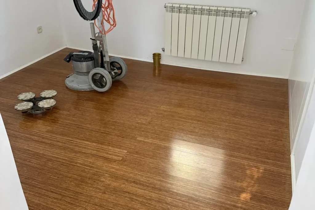 Máquina de lijar de disco sobre un suelo de bambú prensado ya seco, en una habitación vacía