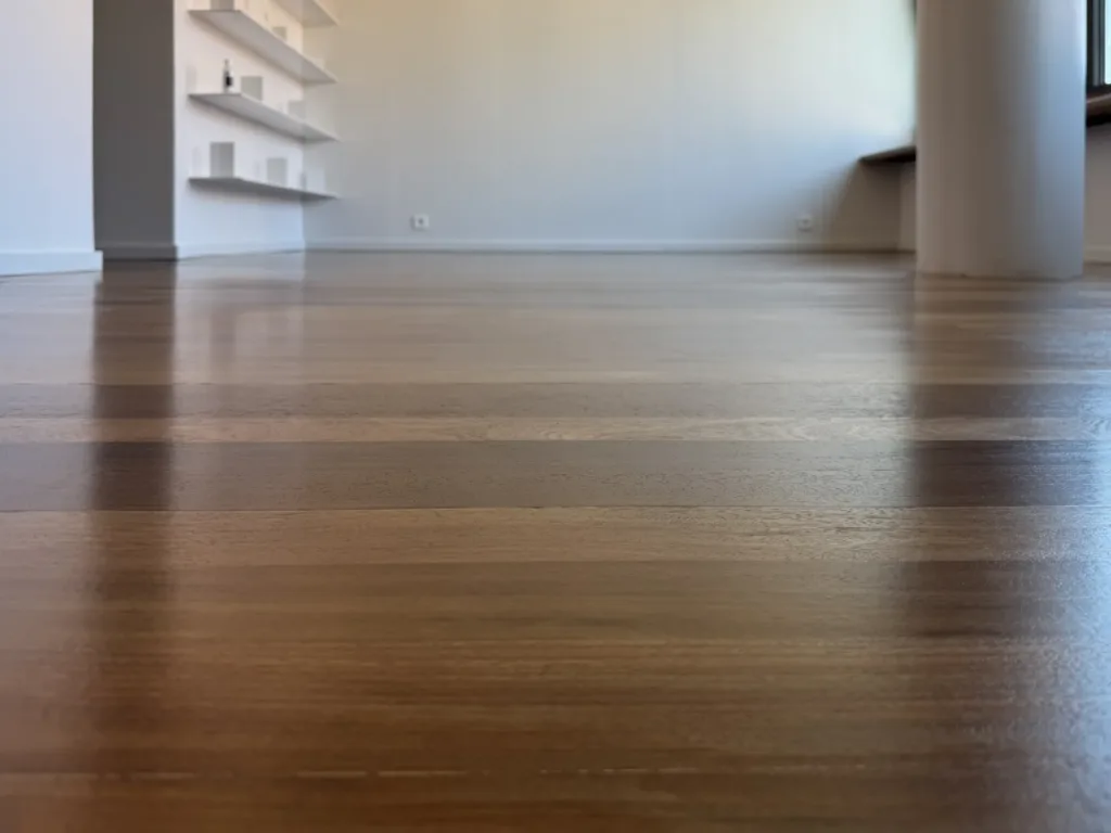 Parquet de maderas tropicales visto a ras de suelo, con barniz Bona Traffic HD satinado, junto a unas baldas blancas