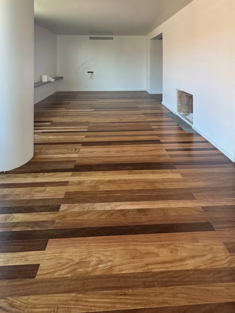 Salón con una columna blanca y parquet de maderas tropicales de varios tonos, restaurado y barnizado