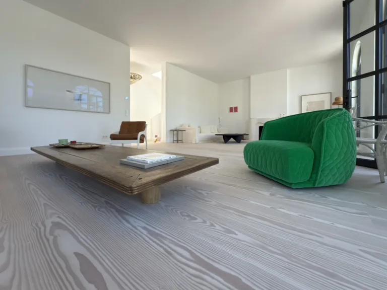 Suelo Dinesen Layers Douglas con lejía y jabón blanco visto a ras de suelo, con una mesa baja de madera y una butaca verde, en una vivienda de Aravaca (Madrid)