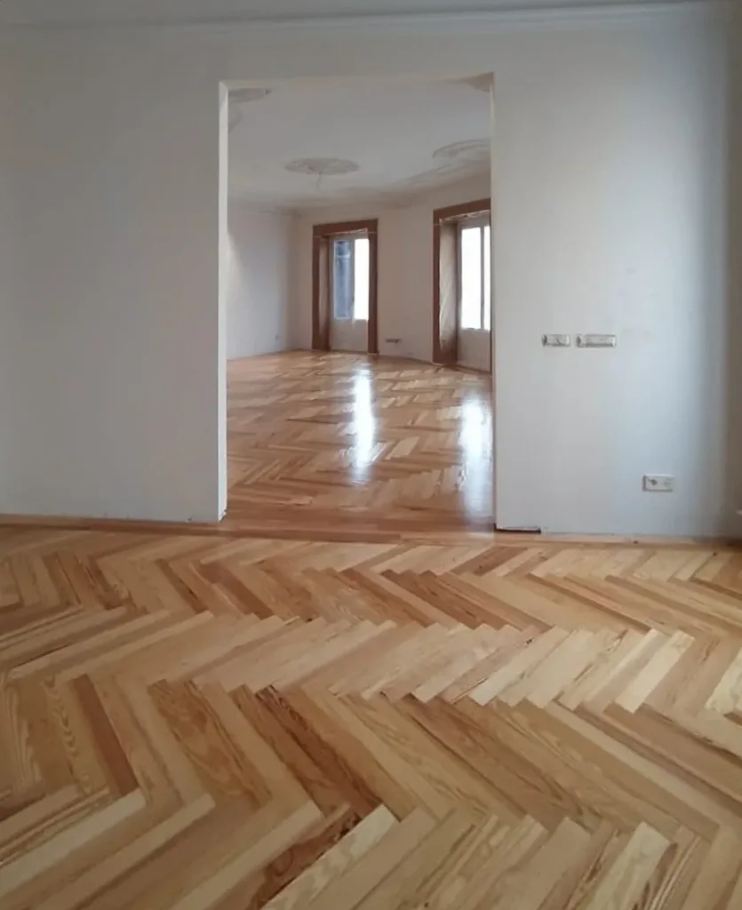 Espiga de pino melis viejo barnizada, con la cenefa de tablas rectas en el paso hacia el salón, vivienda en Chamberí (Madrid)