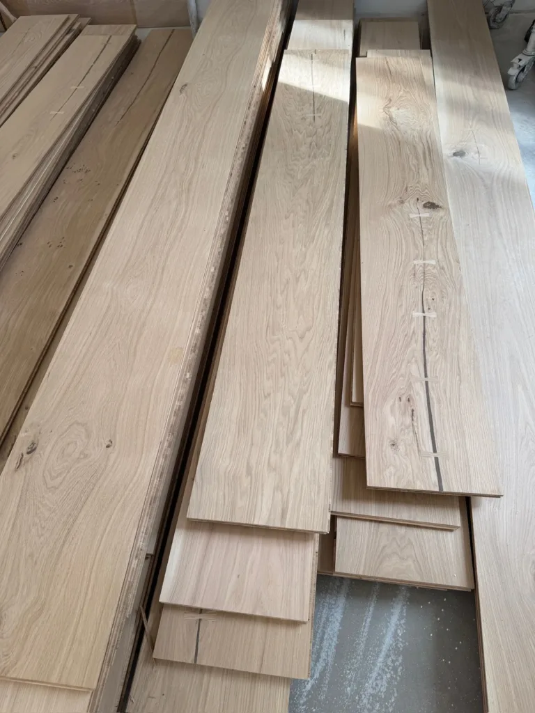 Tablas Dinesen HeartOak apiladas en obra, con las grietas del duramen cosidas con mariposas de roble