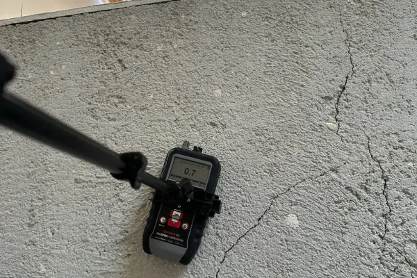 Medida de humedad de la solera Medidor no destructivo de humedad sobre una solera de mortero fisurada durante un peritaje de suelos de madera, en la escala de solado de cemento